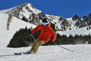 A skier in vibrant winter gear skillfully navigating snowy slopes, surrounded by scenic mountains.